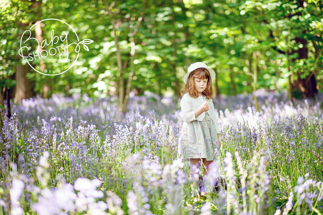 Young girl in hat picking bluebells in the woods in West Sussex