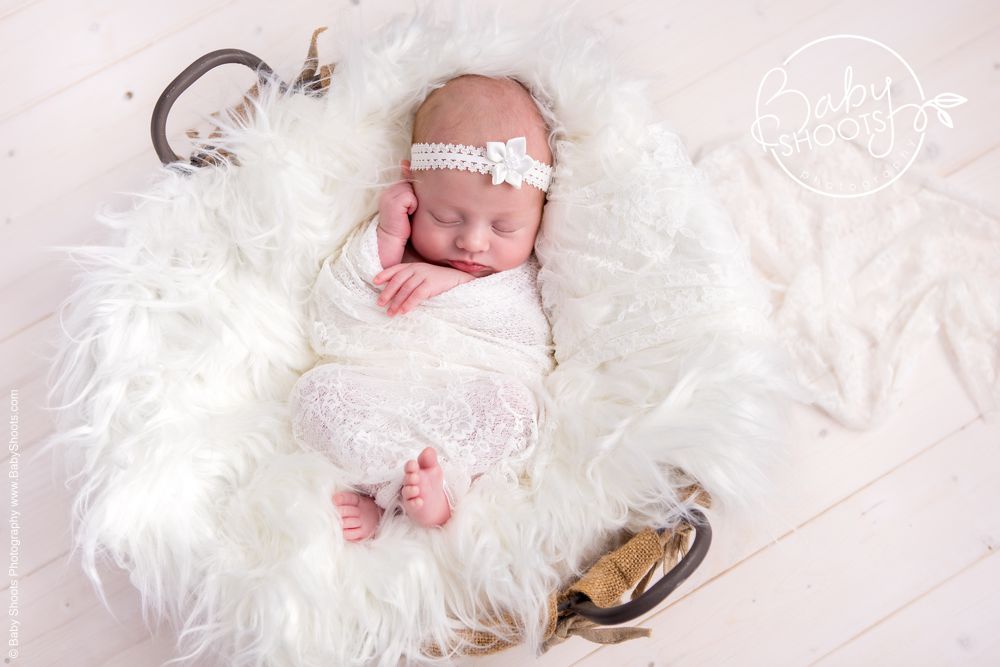 Cute 4 week old baby sleeping in basket with cute white headband