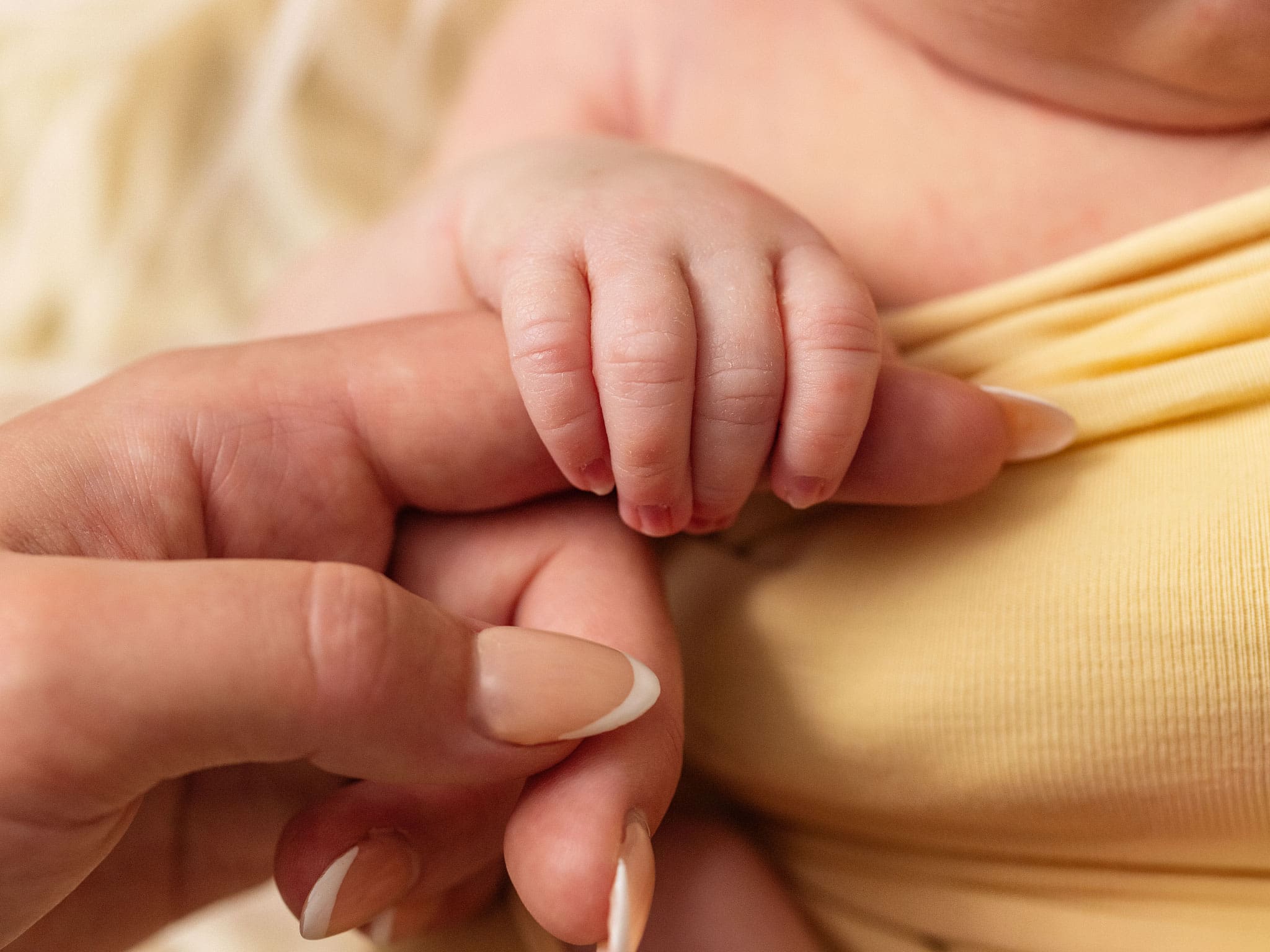 Baby and parent newborn photoshoot Reigate and Redhill showing tiny fingers wrapped around Mum's hand.