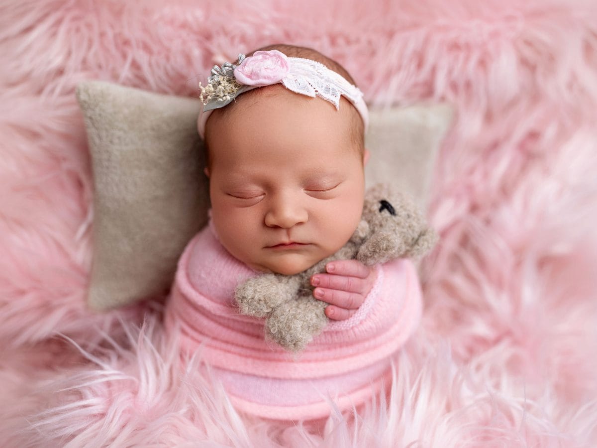 Baby photographer serving Lingfield and the East Grinstead border, capturing a newborn baby in a natural, minimalist style on a soft pink blanket clutching mini teddy bear.