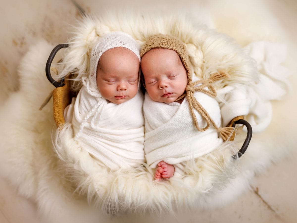 Specialist baby photographer serving Wivelsfield Green and Burgess Hill, capturing a sweet portrait of newborn twins, posed inside a soft and comfortable basket