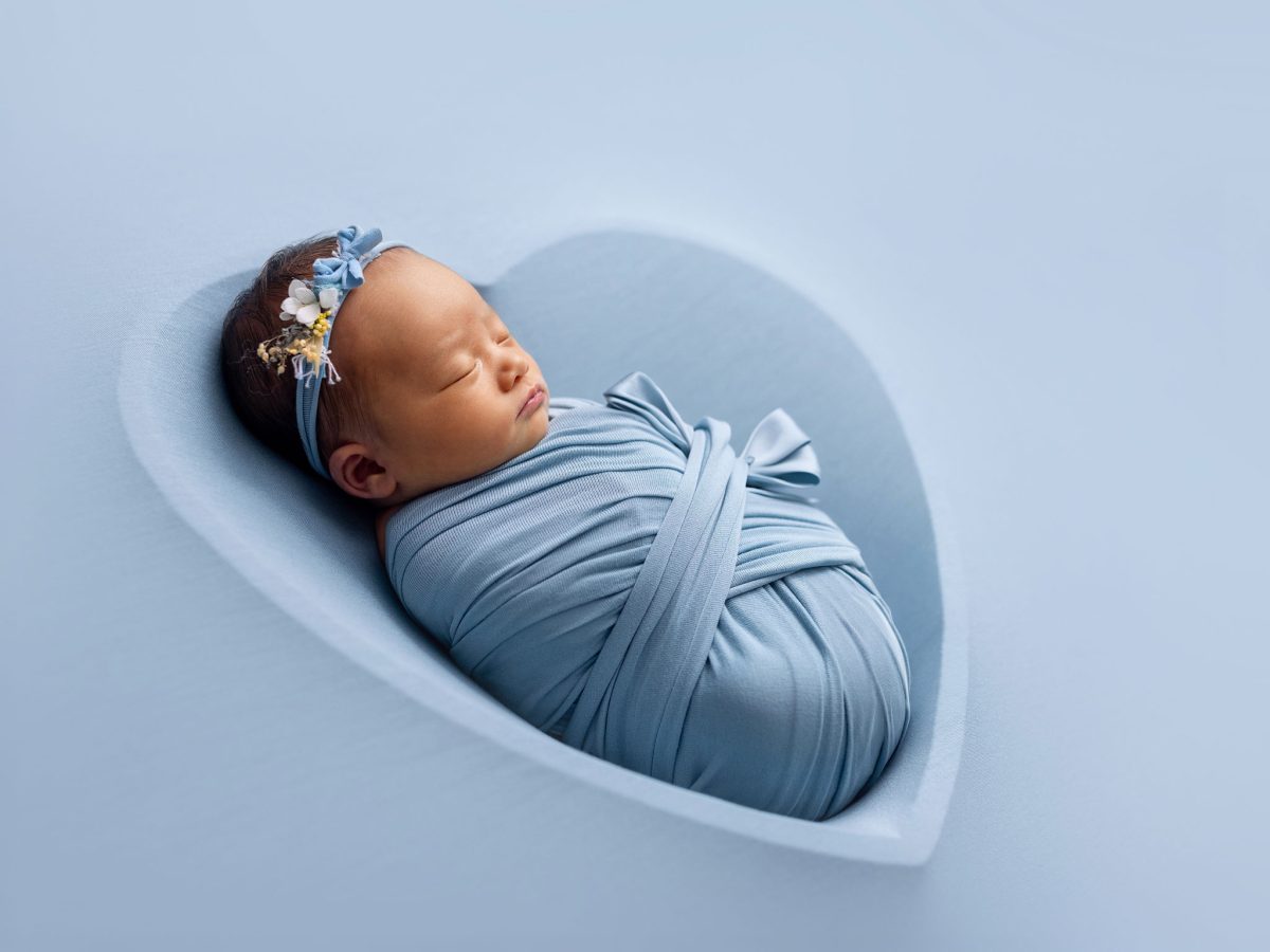 Beautiful baby photos for parents near Ditchling Common and Burgess Hill, featuring a newborn in a heart-shaped bowl with baby blue blanket and floral headband.