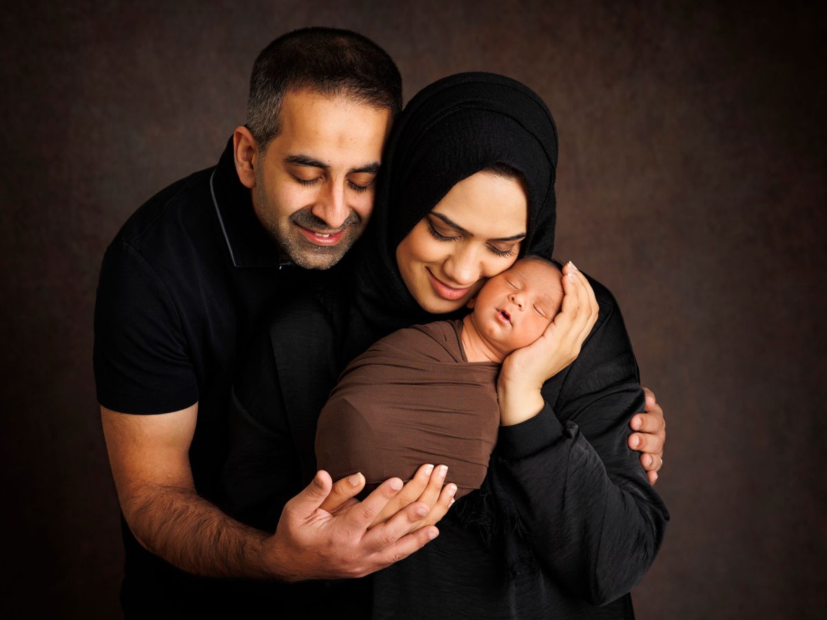 Bespoke newborn portraits for Crawley families. A family newborn photoshoot with baby in parents arms, taken in our specialist newborn photography studio in Copthorne, West Sussex.