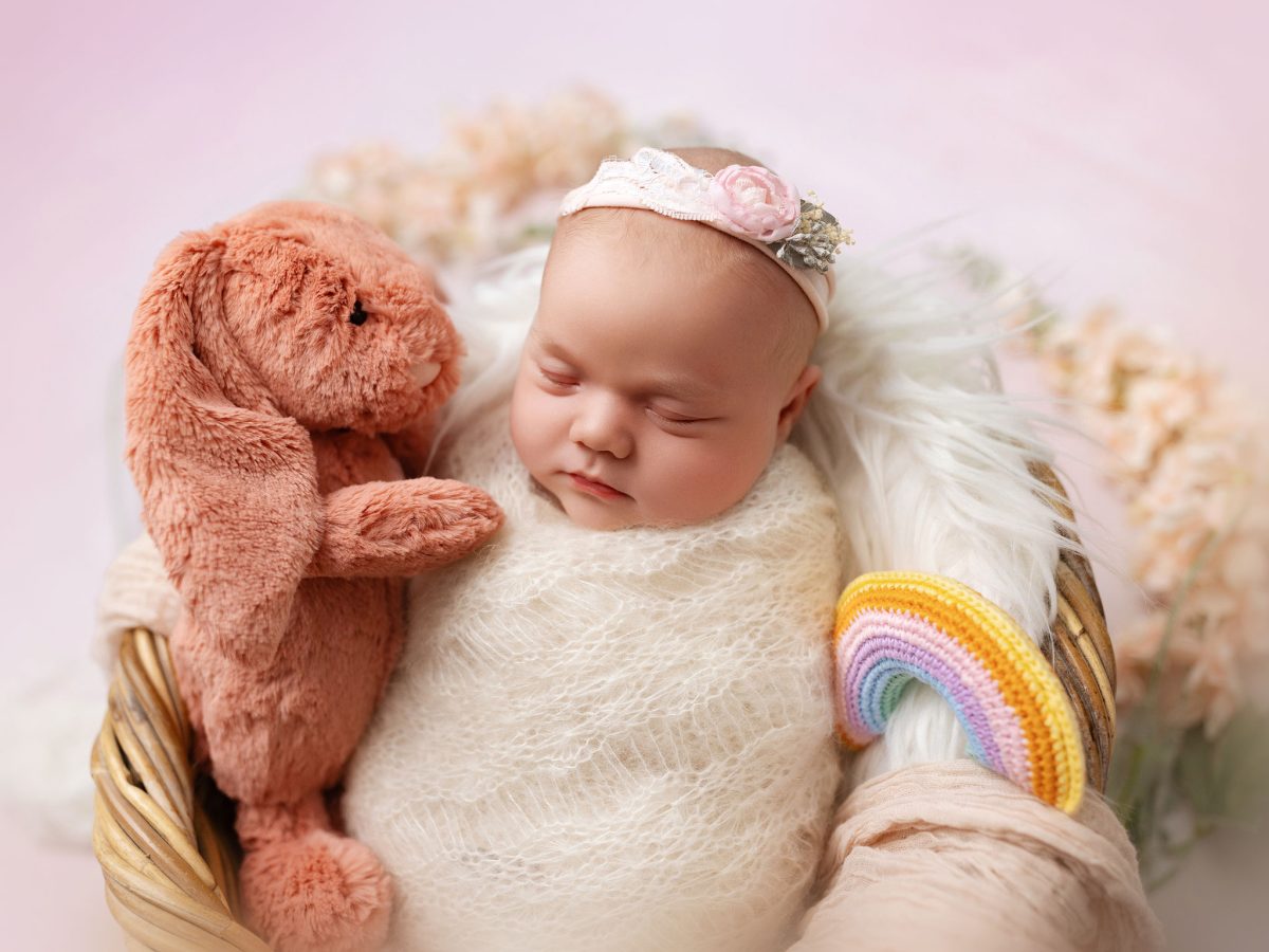Bespoke newborn portraits for Felbridge and East Grinstead parents, capturing the fine details of a newborn baby wrapped in a basket with rainbow.