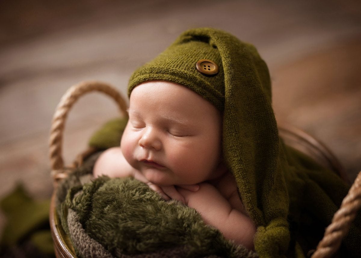 Classic newborn portraits featuring a newborn baby asleep in a cute posing bowl, with sweet little hat.