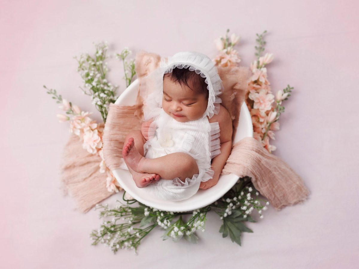 Creative newborn art at our studio near Crawley, West Sussex, featuring a baby posed with delicate floral accessories.