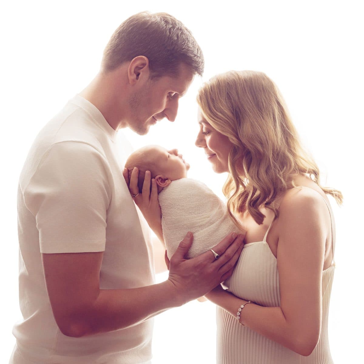 A beautiful, dreamy backlit newborn portrait with parents holding baby. Family newborn photoshoots for parents in RH7 postcode areas.