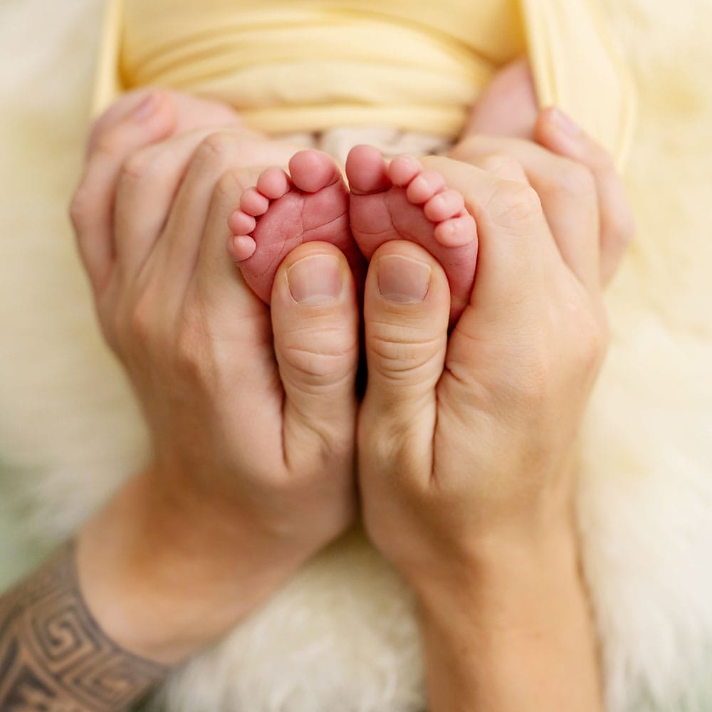 Dad delicately holds his new baby's tiny feet and toes during their Sussex newborn photoshoot at Baby Shoots Photography.
