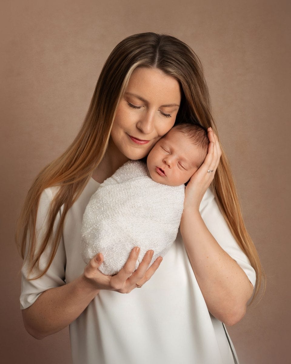 Parent and newborn gallery for Horsham families, featuring a proud new Mum with her new baby held gently in her arms.