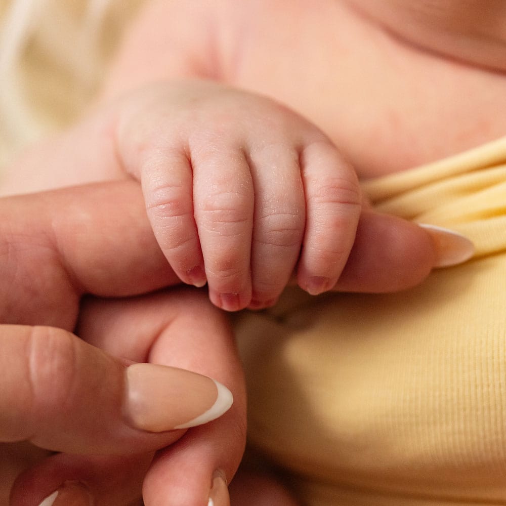 Newborn details captured perfectly by Baby Shoots Photography in West Sussex. A tiny newborn baby grips onto Mum's finger during their first newborn photo session
