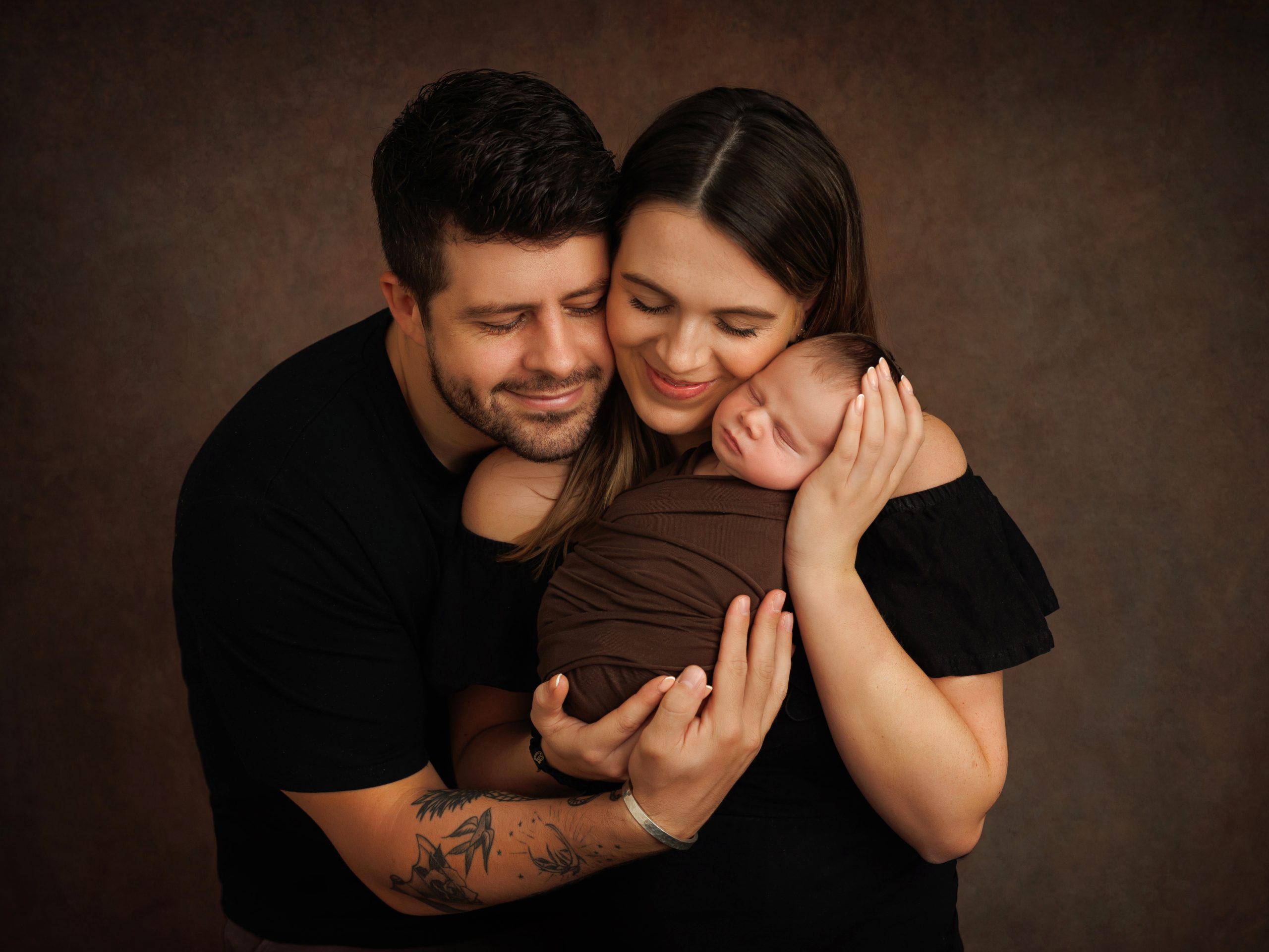 Parents holding their newborn during relaxed studio photography session