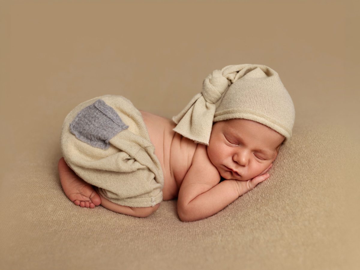 Simple, safe and beautiful newborn photography. A baby slkeeps soundly in a soft pose, on a warm-toned blanket